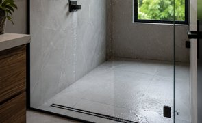 Box de banheiro moderno com piso de porcelanato cinza e ralo linear de aço inox na entrada